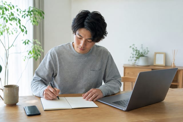 ノートで変えたい条件と残したい条件を整理する会社員